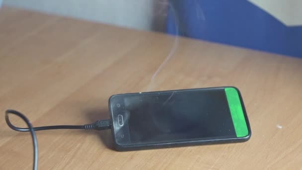 Smartphone è sdraiato sul tavolo e fumare e bruciare. Presto inizierà il fuoco. Concetto di pericolo di incendio. circuito — Video Stock