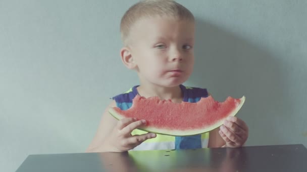 Gelukkig lachende jongen smakelijk eten van rode watermeloen en sap stroomt onder de mond — Stockvideo