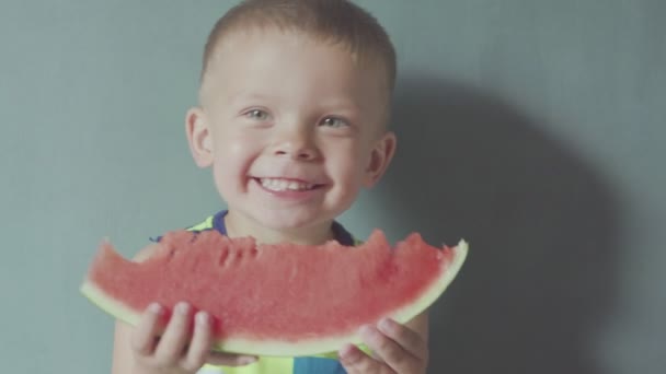 Menino sorridente feliz apetitoso comendo melancia vermelha e suco fluindo sob a boca — Vídeo de Stock