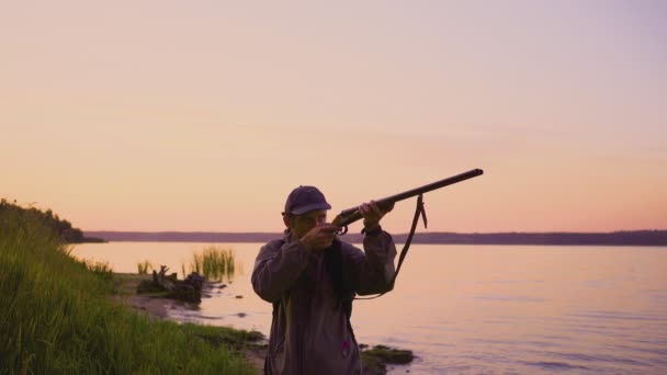 Silhouette du chasseur lors d'une chasse au canard près d'un beau lac. Chasseur de tir . — Video