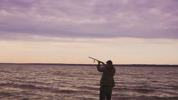 Silhouette del cacciatore in una caccia all'anatra vicino a un bellissimo lago. Cacciatore di tiro . — Video Stock