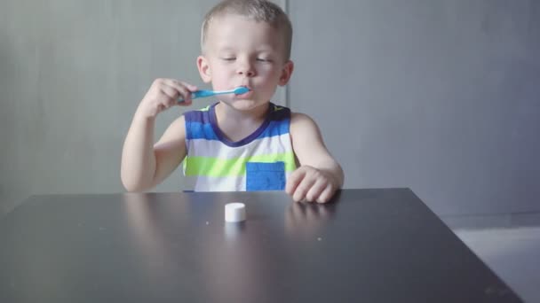 Малыш чистит зубы в ванной, улыбается, светло-серый фон — стоковое видео