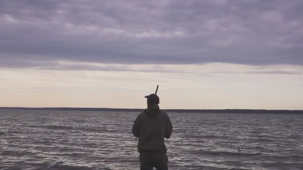 Silhouette del cacciatore in una caccia all'anatra vicino a un bellissimo lago. Cacciatore di tiro . — Video Stock