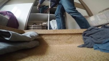 Bir adam kıyafetleri olan bir bavulu boşaltır..