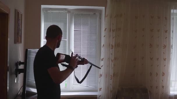 Człowiek z pistoletu, patrząc przez okno. ochroniarz i Samoobrona koncepcja, inaczej rabuś, morderca i złodziej. — Wideo stockowe