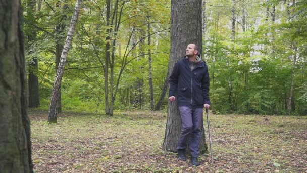 Молодой человек ходит на костылях в осеннем парке — стоковое видео