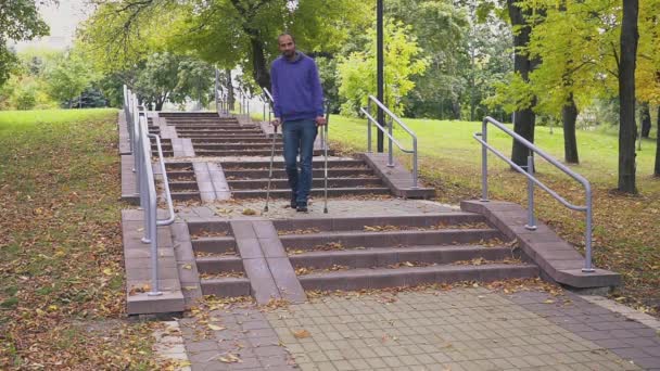 Egy mankós férfi felmászik egy lépcsőn. Az inkluzív társadalomra vonatkozó koncepció — Stock videók