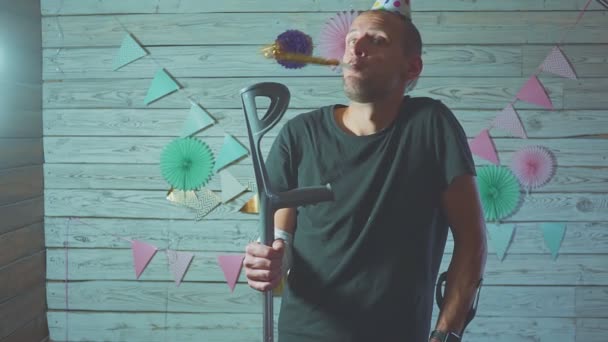 Раненый мужчина празднует день рождения дома с костылями в руке — стоковое видео