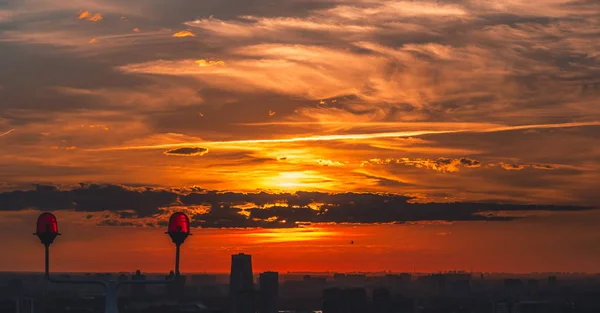 迷人的橙色日落在城市设置拍摄从高点从摩天大楼与 Silhouetes 的建筑物下面 太阳隐藏的云 红色信号灯设置在屋顶上的前景 — 图库照片