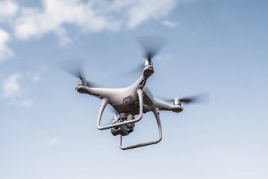 UAV quadcopter bir dijital fotoğraf makinesi ile bir yayın çekiyor; Beyaz uçan uçağın arka planda parlak gökyüzü ile test uçuşu yapıyor