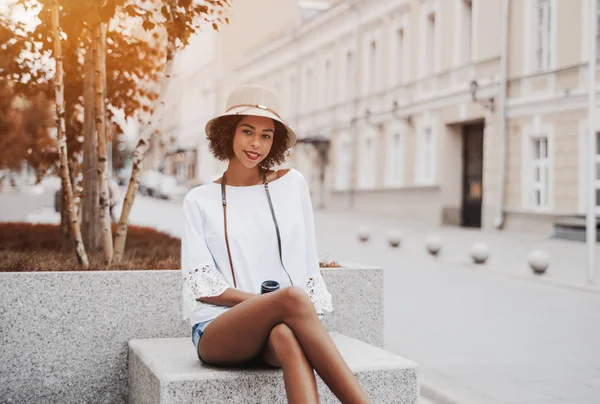 Çok güzel bir genç siyah erkek gülümseyen mermer bir adımla açık havada huş arkasında üzerinde oturuyor; neşeli seksi Afrikalı-Amerikalı kız kıvırcık afro saçlı dışında bir ev arkasında oturuyor