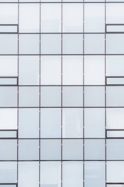 Bir ofis binası cephesi düz cam pencere ve pencere ile dikey doku yansıtıcı mavimsi gökyüzü degrade yapraklar; kısmen görünür iş ofis Odalar cam arkasında