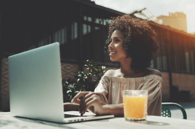 Açık havada laptop ve lezzetli portakal suyu ile sokak bir barda oturmuş neşeli genç Afro-Amerikan erkek; güzel Brezilyalı kadın freelancer net-kitap ile sokak Cafe