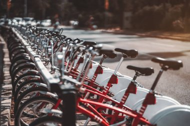 Kendi park yerine park ve mesafe içine uzanan takılı kırmızı kiralık bisikletler satırın alan sığ derinliği ile yakından görmek; güçlü bokeh, güneşli bir gün, Barcelona, İspanya