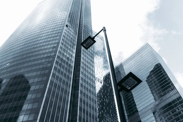 Ön planda, büyük iş ofis gökdelenler ile cam cepheler arka planda ufuk mavimsi renk renk, farklı yükseklik düzeyde iki lamba ile modern sokak fener gün bulutlu