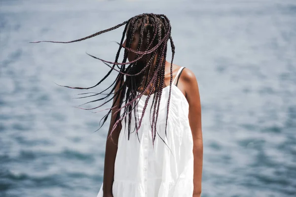 若いアフリカお下げと白いドレスを着た女性は彼女の頭部から左右に揺れ 暖かい夏の日に海の横に立ってよそ見 黒の少女風フリル編みこみ髪 — ストック写真