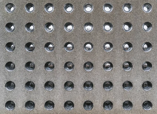 Modern concrete fence with glass insertions; a grainy texture of contemporary stone block with round holes inserts made of clean glossy partially transparent glass; the fragment of a concrete wall — Stock Image Modern Concrete Fence Glass Insertions Grainy Texture Contemporary Stone Block Stock Photo