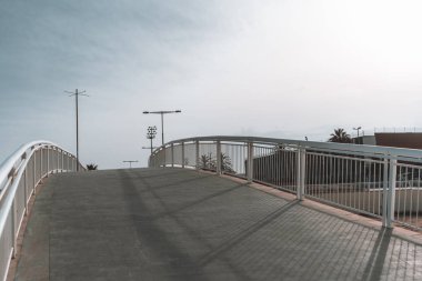 Boş patika ile bükülmüş yaya köprüsü: geniş açı çekim, akşam temiz gökyüzü ile uzun gölgeler, kaldırım taş zemin, Polonyalılar ve sokak uzakta, Barcelona, İspanya