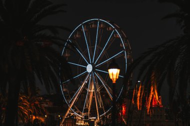 Gece karanlık siluetleri avuç içi ve tek bir sokak fener ön planda, Cascais, Portekiz ile çerçeveli güzel ışıklı bir dönme dolap ile vurdu