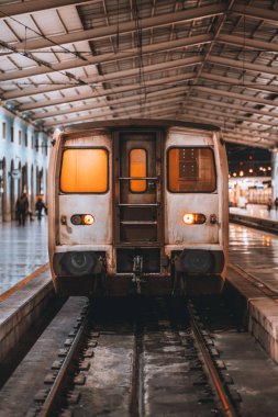 Bir dikey ön görünümünü bir grungy lokomotif kabin kapalı bir tren istasyonu depo bakım sırasında; yatılı, Lizbon için bekleyen bir banliyö vagon ile gece tren istasyonu platformu