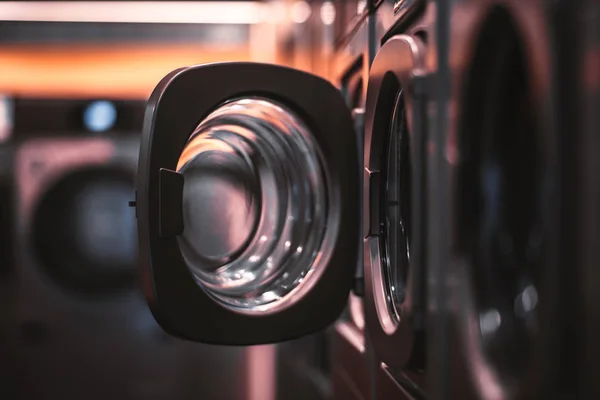 Karanlık bir odada birden fazla çamaşır makineleri içinde açık kapı sığ derinlik-in tarla, güçlü bokeh bir çamaşır kurutma makinesi, tarih seçici odak ile ortak bir çamaşır