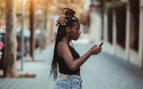 Czarna dziewczyna na zewnątrz za pomocą telefonów komórkowych — Zdjęcie stockowe