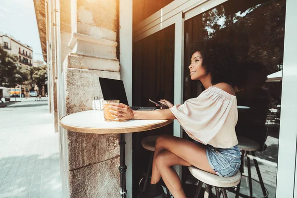 Chica en un bar con ordenador portátil y teléfono — Foto de Stock