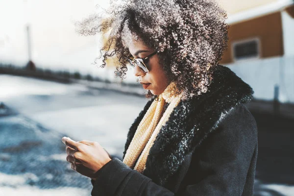 Curly mixed girl is texting outdoors — Stock Photo, Image