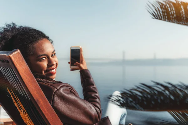 Ragazza con smartphone sulla poltrona reclinabile — Foto Stock