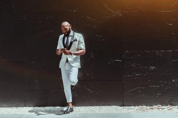 Hombre negro con teléfono inteligente cerca de la pared —  Fotos de Stock