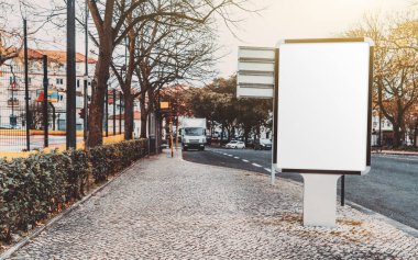 Yolun yakınındaki bir kaldırım taşında boş beyaz reklam panosu şablonu; kaldırımda boş reklam afişi taşıyıcı şablonu; sol tarafta bir kopya alanı olan kentsel ayarlarda poster modeli