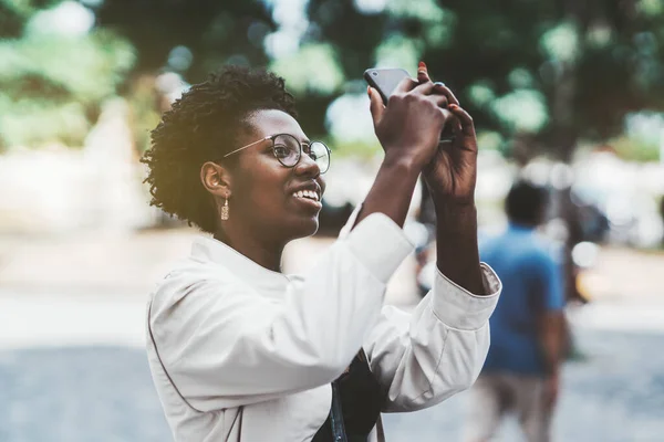Młoda Szczęśliwa Afrykańska Kobieta Fotografuje Zwiedzanie Zewnątrz Pomocą Telefonu Komórkowego — Zdjęcie stockowe