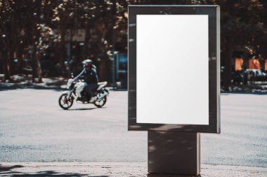 Boş poster modeli şehir ayarları ile yol ve bir motosikletçi geçmekte olan sönmüş bir arka plan; boş bir reklam afiş şablonu arkasında bir motosikletçi ile dışarıda yer tutucu