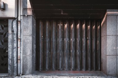 Garaj ya da giriş kapalı metal kapı dokusu, kapının kahverengi dikey yelpaze çizgileri ile; Lizbon, Portekiz 'de yaygın olarak kullanılan büyük bir kapının akordeon katlı boyalı kapısı ön görünümü