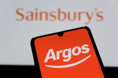 Bandung, Indonesia - September 15, 2025: In This illustration photo shows the Argos logo displayed on a smartphone with Sainsbury's logo in the background. 
