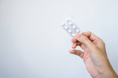 Bir el, iki hap dozunda ilaç içeren bir ilaç paketini gösteriyor. Kişinin sağlığının, sağlık durumunun ve sorumluluğunun ne kadar önemli olduğunu gösteriyor.