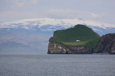 Arka planda Eyjafjallajokull buzulu bulunan Vestmannaeyjar takımadasındaki İzlanda adası