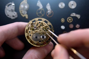 Saatçi atölyesindeki mekanik saatleri tamir ediyor.