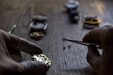 Saatçi eski bir vekanik saati tamir ediyor.