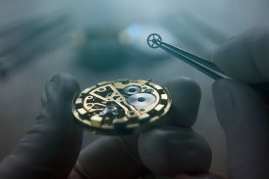 Saatçi atölyesindeki mekanik saatleri tamir ediyor.