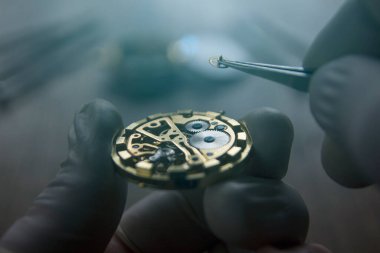 Saatçi atölyesindeki mekanik saatleri tamir ediyor.