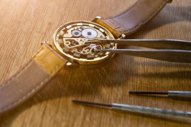 Saatçi atölyesindeki mekanik saatleri tamir ediyor.