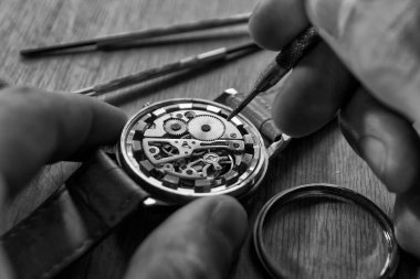 Saatçi atölyesindeki mekanik saatleri tamir ediyor.