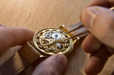 Saatçi atölyesindeki mekanik saatleri tamir ediyor.