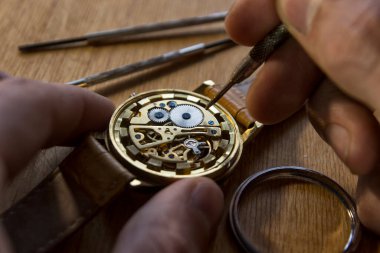 Saatçi atölyesindeki mekanik saatleri tamir ediyor.