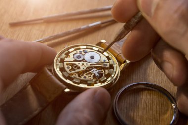 Saatçi atölyesindeki mekanik saatleri tamir ediyor.