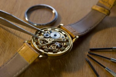 Saatçi atölyesindeki mekanik saatleri tamir ediyor.