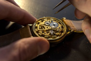 Saatçi atölyesindeki mekanik saatleri tamir ediyor.