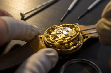 Saatçi atölyesindeki mekanik saatleri tamir ediyor.