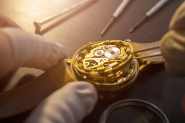 Saatçi atölyesindeki mekanik saatleri tamir ediyor.